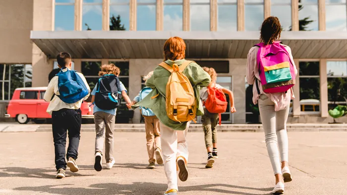 Schulkinder gehen auf den Eingang eines Schulgebäudes zu